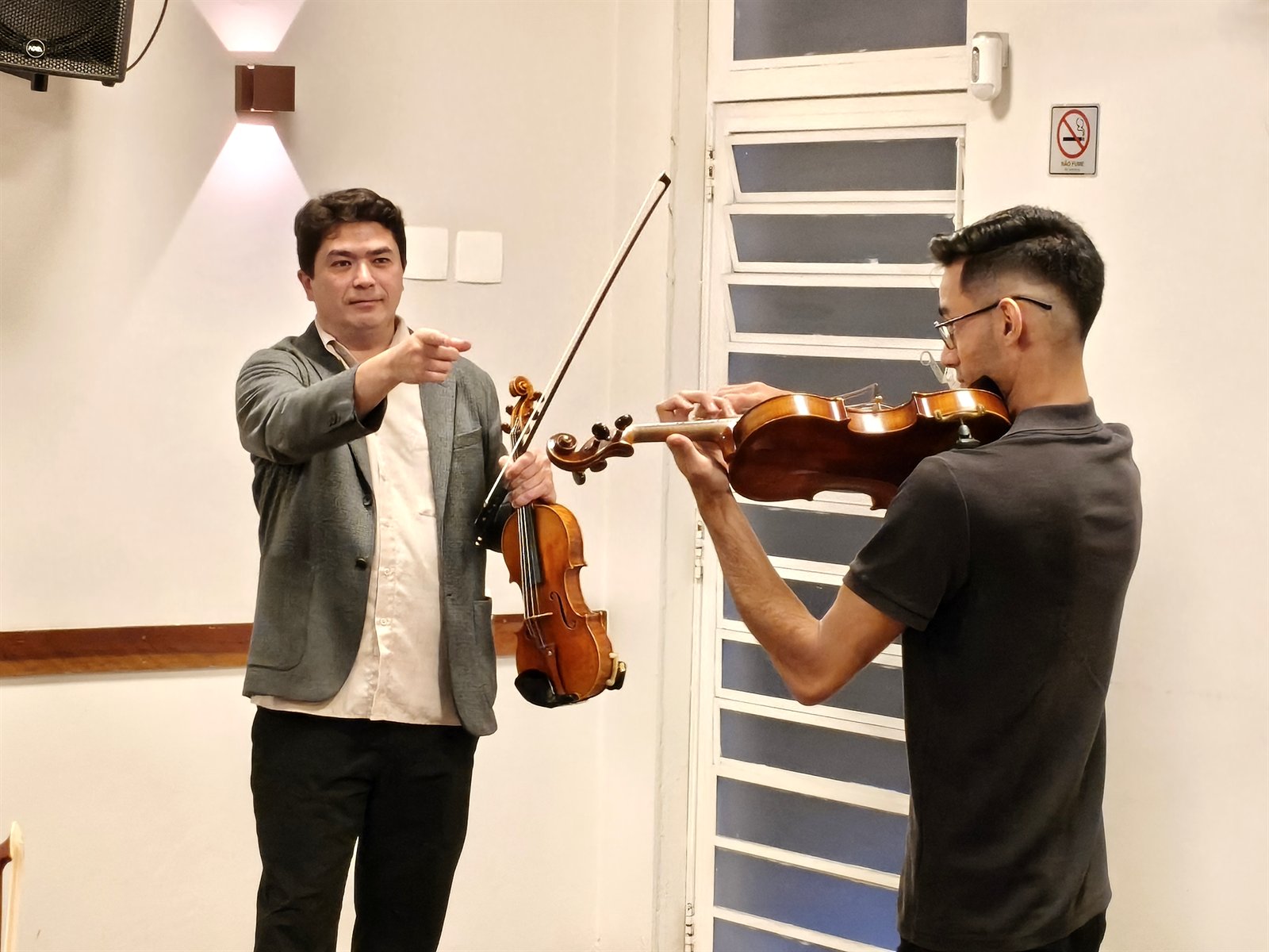 Violinista Omar Guey orientando aluno durante masterclass de violino