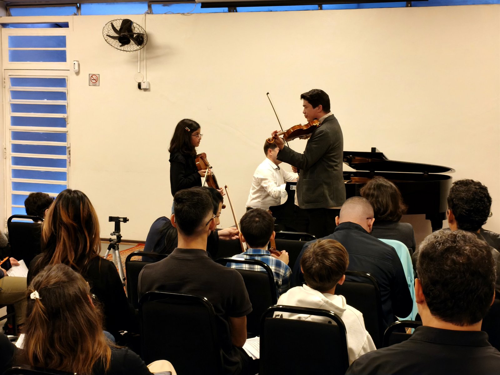 Omar Guey conduzindo masterclass de violino diante de plateia de alunos